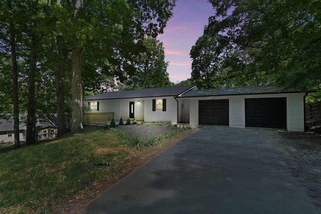 ranch-style home with driveway, metal roof, and a garage