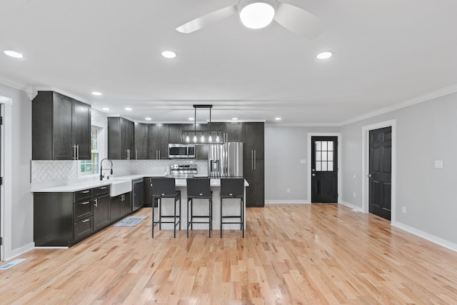 kitchen with dark cabinetry, backsplash, a kitchen bar, appliances with stainless steel finishes, and ornamental molding