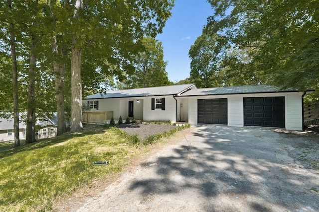 single story home featuring a garage, aphalt driveway, and metal roof
