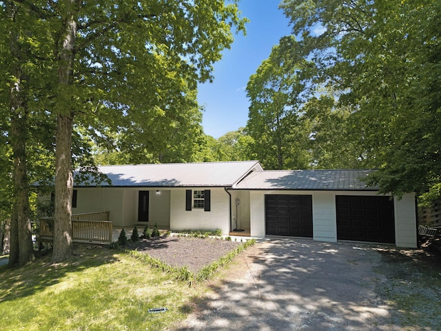 ranch-style home with an attached garage, driveway, metal roof, and brick siding
