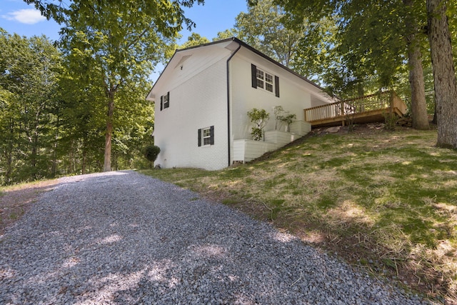 view of side of home featuring brick siding and a wooden deck