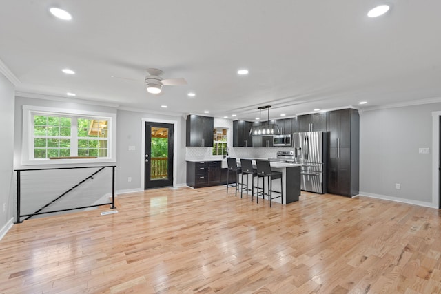 kitchen featuring crown molding, light countertops, appliances with stainless steel finishes, and a breakfast bar area