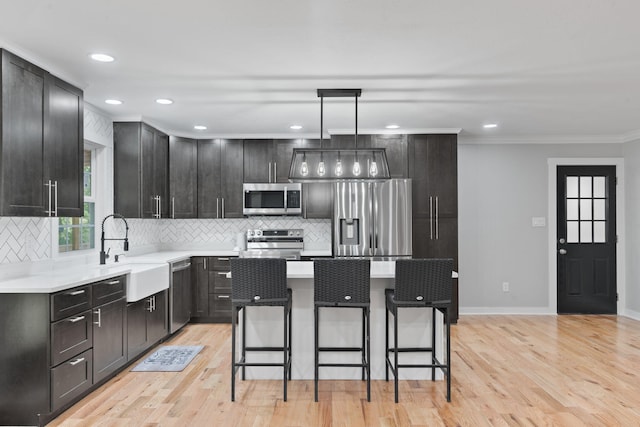 kitchen with decorative backsplash, a breakfast bar area, light wood-type flooring, a sink, and appliances with stainless steel finishes