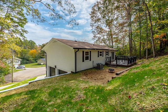 back of property featuring central AC unit, a garage, a wooden deck, and a lawn