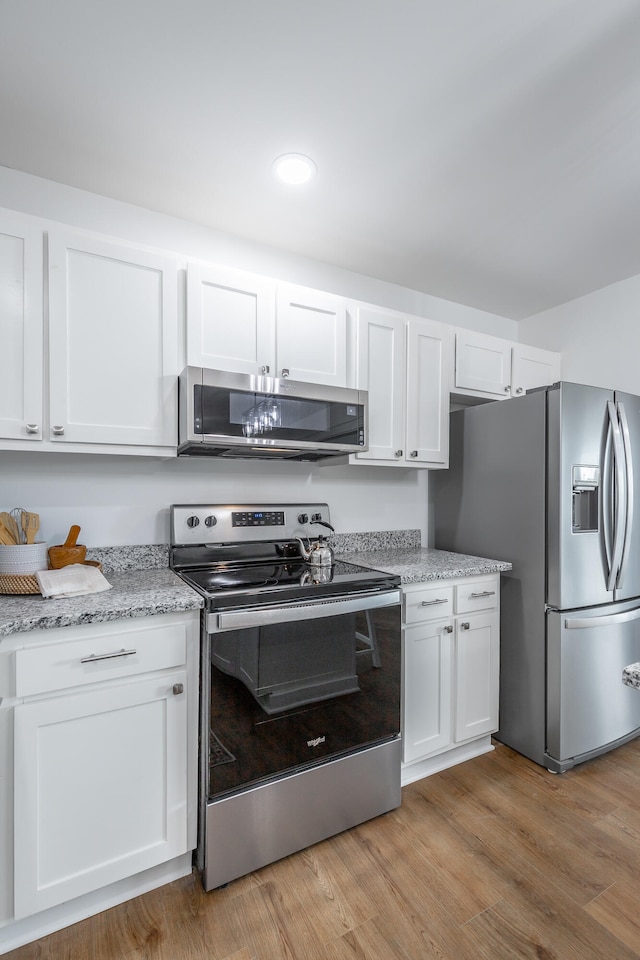 kitchen featuring white cabinetry, light hardwood / wood-style flooring, stainless steel appliances, and light stone counters