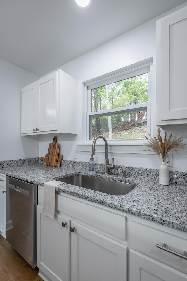 kitchen featuring light stone counters, stainless steel dishwasher, sink, dark hardwood / wood-style floors, and white cabinetry