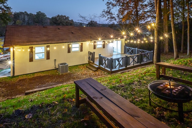 back house at dusk featuring an outdoor fire pit, central AC, and a deck