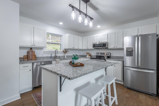 kitchen featuring a kitchen island, white cabinetry, dark wood-type flooring, and appliances with stainless steel finishes