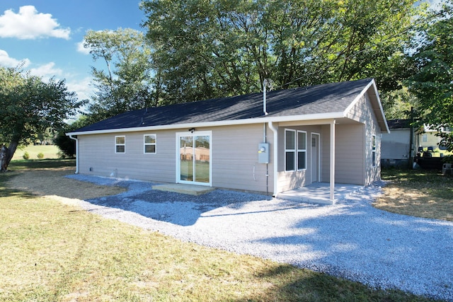 rear view of house featuring a yard, roof with shingles, and a patio