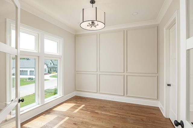 interior space with wood-type flooring, an inviting chandelier, a healthy amount of sunlight, and crown molding