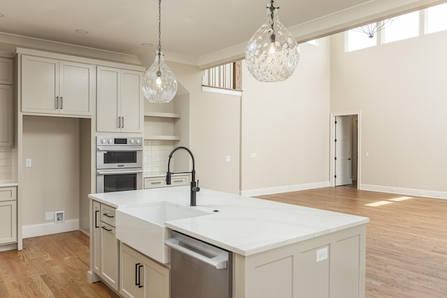 kitchen with hanging light fixtures, light stone countertops, backsplash, and appliances with stainless steel finishes