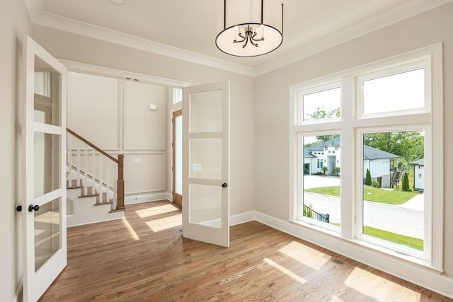 interior space with a chandelier, french doors, crown molding, and hardwood / wood-style floors