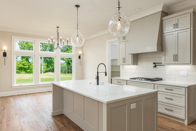 kitchen featuring light stone counters, an island with sink, light hardwood / wood-style floors, and stainless steel gas stovetop