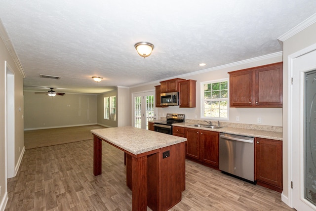 kitchen featuring a center island, sink, ceiling fan, a textured ceiling, and stainless steel appliances