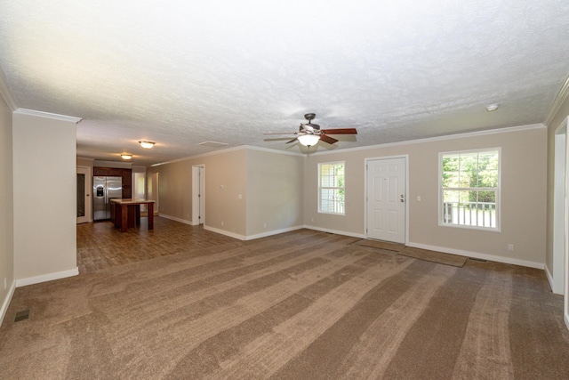 unfurnished living room featuring dark carpet, ornamental molding, a textured ceiling, and a wealth of natural light