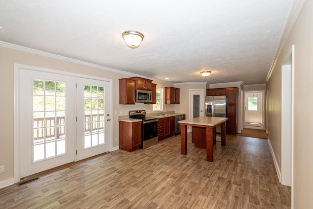 kitchen featuring sink, ornamental molding, a textured ceiling, light hardwood / wood-style floors, and stainless steel appliances