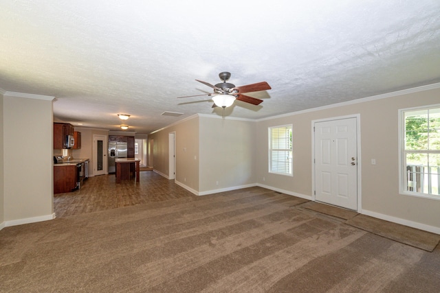 unfurnished living room featuring ceiling fan, dark carpet, a textured ceiling, and ornamental molding