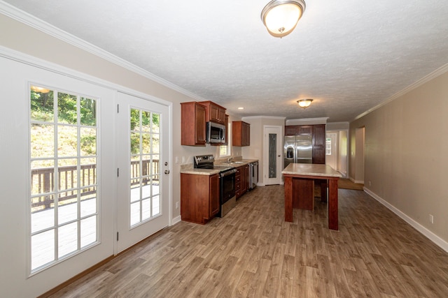 kitchen with a textured ceiling, stainless steel appliances, crown molding, wood-type flooring, and a center island