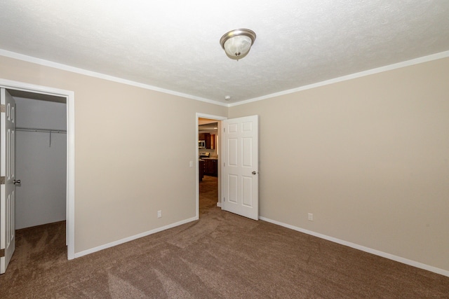 unfurnished bedroom with crown molding, carpet flooring, a spacious closet, a textured ceiling, and a closet