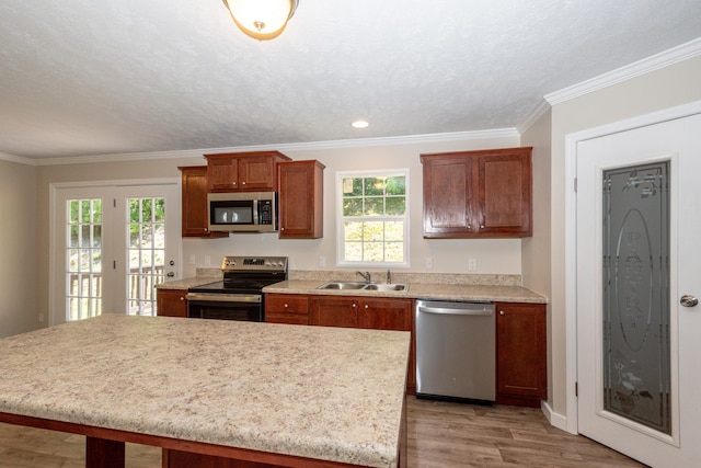 kitchen with a center island, crown molding, sink, light wood-type flooring, and stainless steel appliances