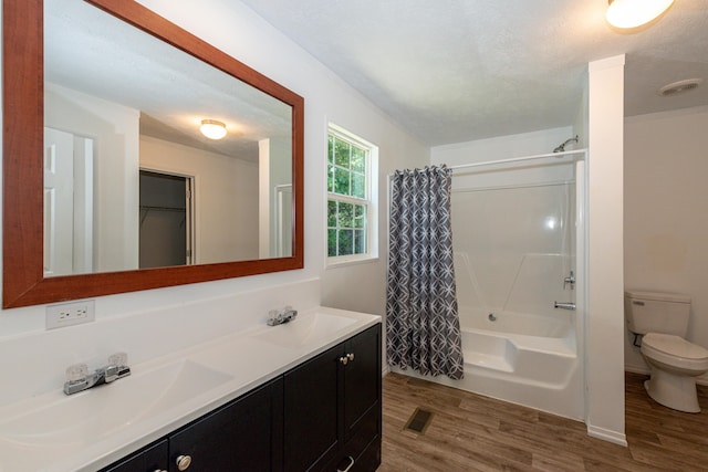 full bathroom featuring vanity, a textured ceiling, wood-type flooring, shower / bathtub combination with curtain, and toilet