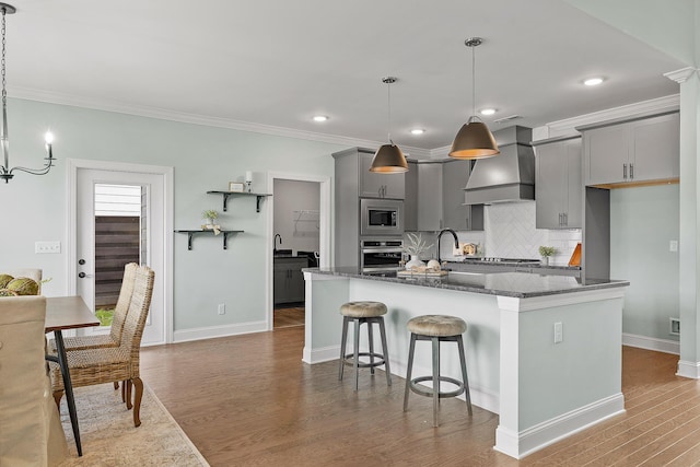 kitchen featuring gray cabinets, hanging light fixtures, stainless steel appliances, and custom range hood