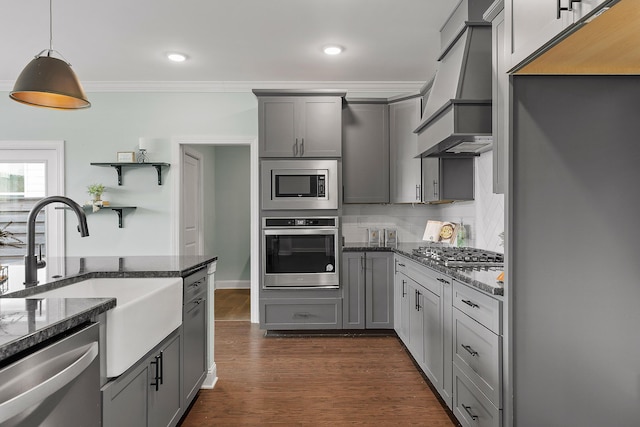 kitchen with dark stone counters, decorative light fixtures, gray cabinets, appliances with stainless steel finishes, and custom exhaust hood