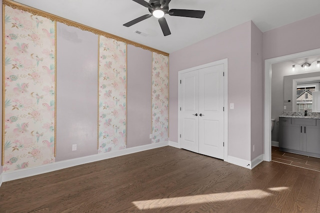 unfurnished bedroom featuring ceiling fan, ensuite bathroom, and dark wood-type flooring