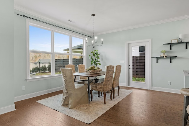 dining space featuring dark hardwood / wood-style flooring, crown molding, and a chandelier