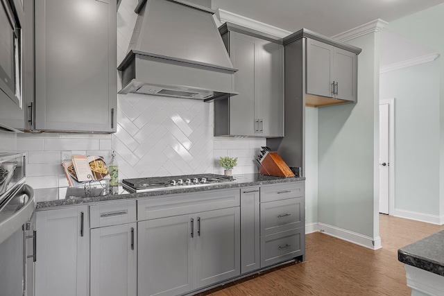 kitchen with premium range hood, gray cabinetry, crown molding, and stainless steel gas stovetop