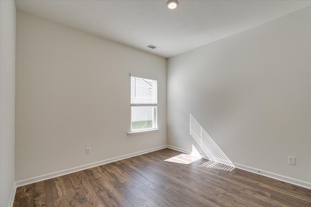 spare room with dark hardwood / wood-style floors and a textured ceiling