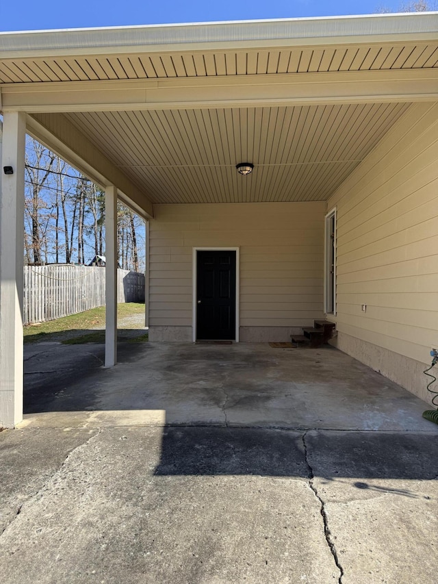 view of patio / terrace with entry steps, an attached carport, fence, and driveway