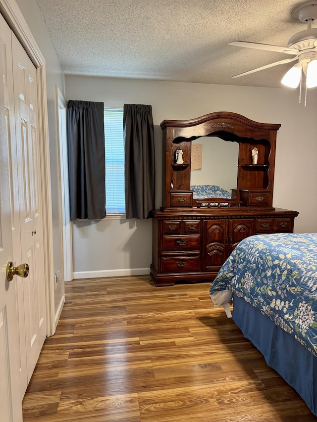 bedroom with baseboards, a textured ceiling, wood finished floors, and a ceiling fan