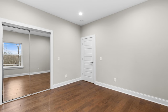 unfurnished bedroom with dark hardwood / wood-style floors and a closet