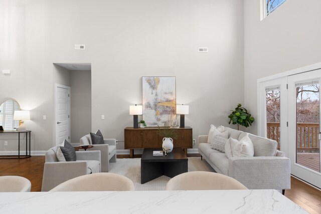 living room with a towering ceiling, a wealth of natural light, and wood-type flooring