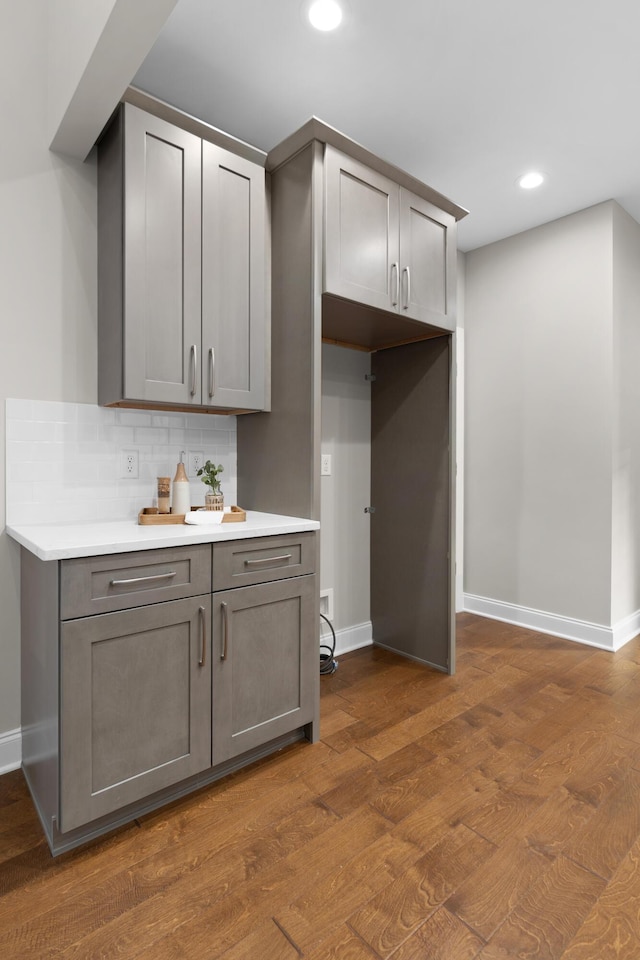 kitchen with gray cabinetry, dark hardwood / wood-style floors, and decorative backsplash
