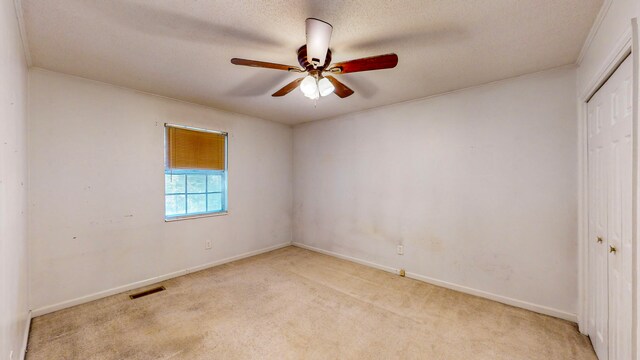 empty room with light carpet, a textured ceiling, and ceiling fan