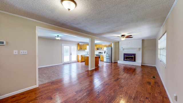 unfurnished living room featuring a fireplace, hardwood / wood-style floors, a textured ceiling, and ornamental molding