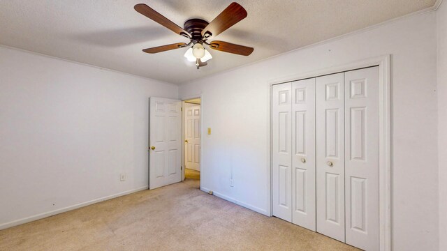 unfurnished bedroom with ceiling fan, a closet, light carpet, and a textured ceiling