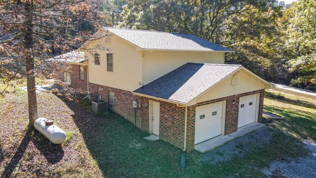 view of side of home with central air condition unit and a garage