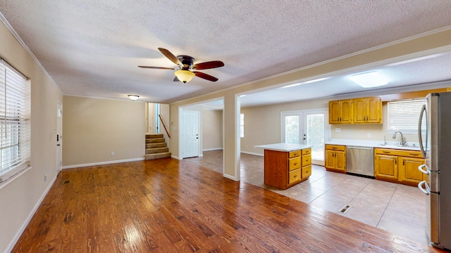 kitchen featuring sink, stainless steel appliances, light hardwood / wood-style flooring, a textured ceiling, and ornamental molding