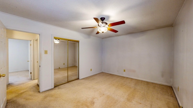 unfurnished bedroom featuring ceiling fan, a closet, light carpet, and a textured ceiling