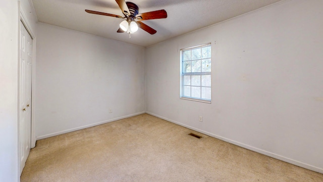 carpeted spare room featuring ceiling fan and ornamental molding