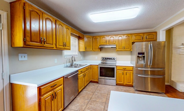 kitchen with a textured ceiling, stainless steel appliances, ornamental molding, and sink