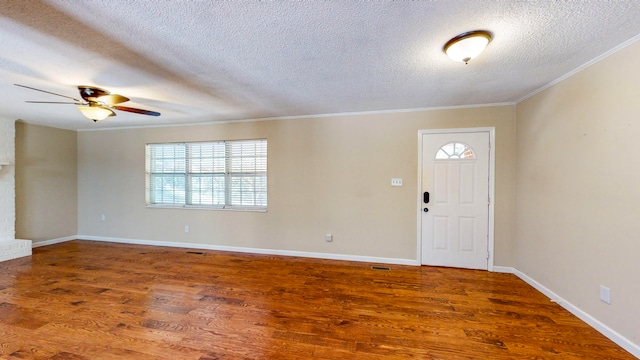 entrance foyer with a brick fireplace, ornamental molding, a textured ceiling, ceiling fan, and hardwood / wood-style floors