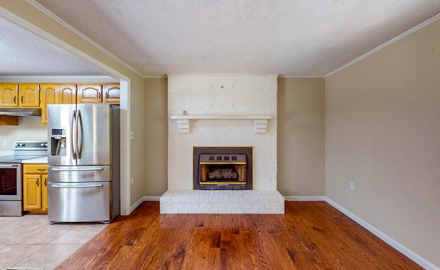 kitchen with a fireplace, stainless steel appliances, a textured ceiling, and wood-type flooring