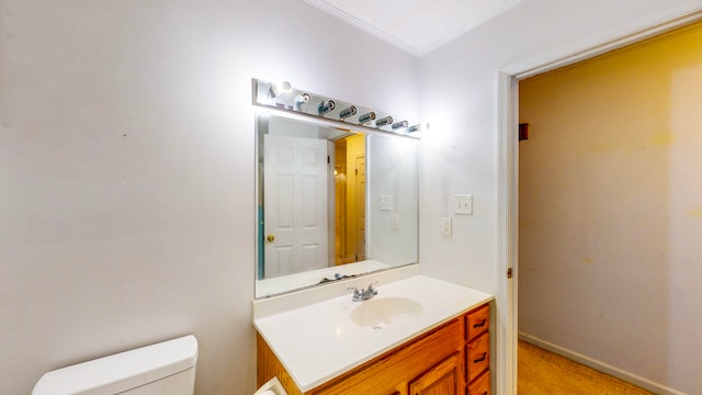 bathroom with vanity, toilet, and ornamental molding