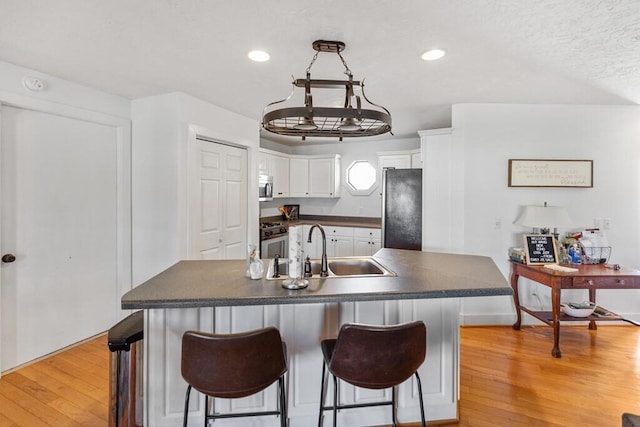 5027 Fanchers Mill Rd, Sparta, TN 38583 - kitchen featuring appliances with stainless steel finishes, dark countertops, a sink, white cabinets, and light wood finished floors