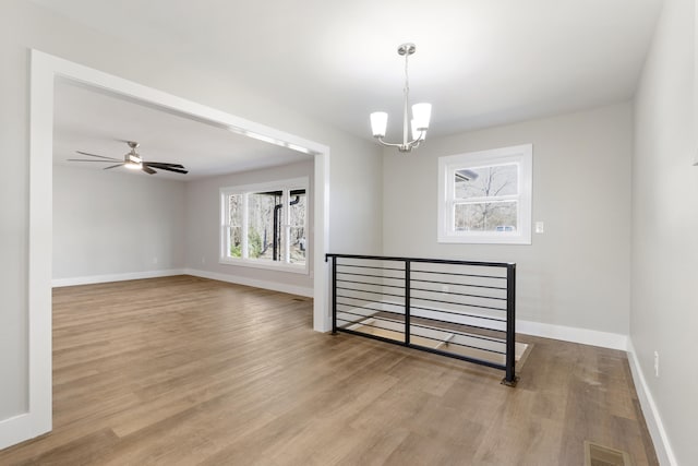 spare room featuring ceiling fan with notable chandelier and light hardwood / wood-style flooring