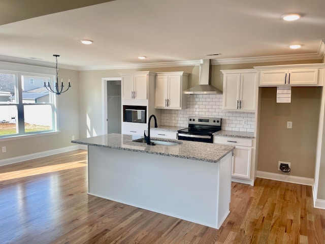 kitchen featuring wall chimney range hood, sink, stainless steel electric range oven, light stone counters, and white cabinetry